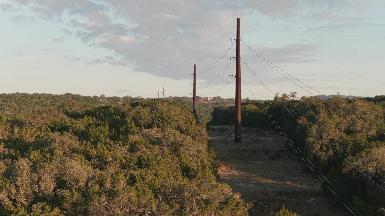 Transmission lines and a cleared utility corridor through wooded terrain