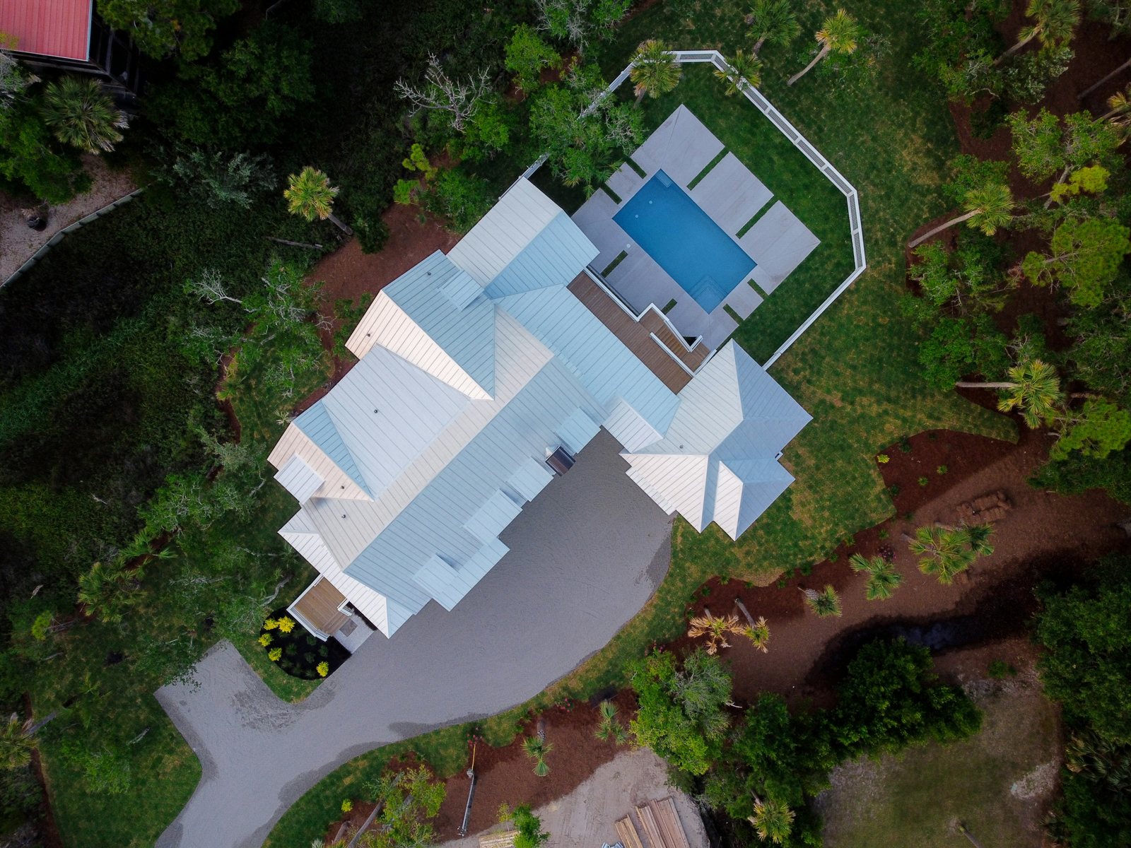 Top-down aerial view of a house, pool, landscaping, and driveway