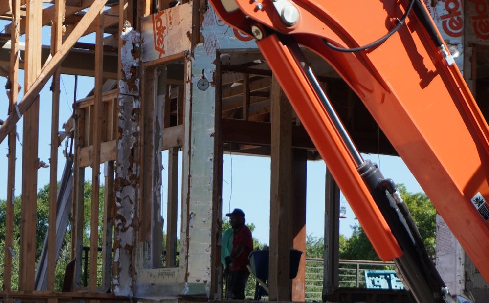 Framing stage of a Central Texas custom build, excavator on site